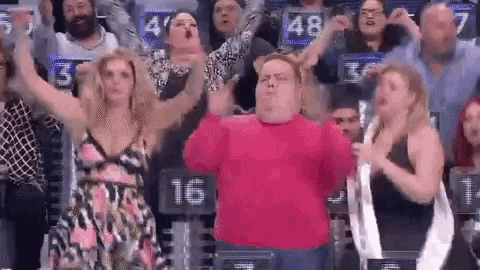 a man in a pink shirt is dancing in front of a crowd of people