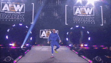 a wrestler is walking down the aisle in front of a sign that says all elite aew wrestling dark elevation