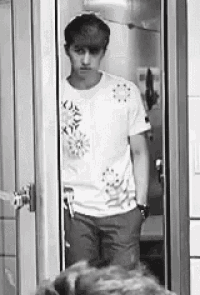 a man in a white shirt is standing in front of a door .