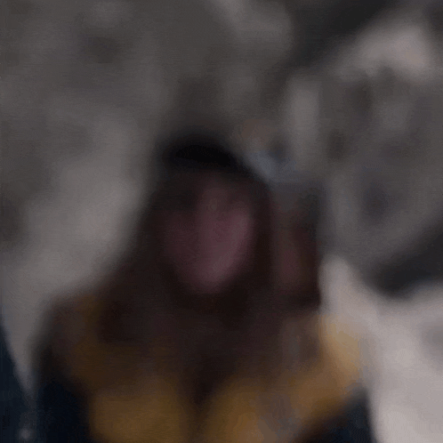 a blurry picture of a person wearing a jacket and a hat .