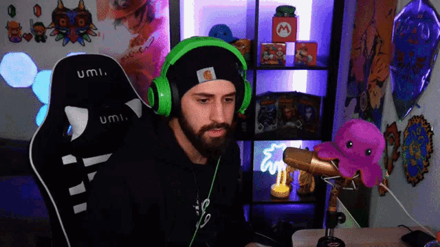 a man wearing green headphones sits in a umi gaming chair