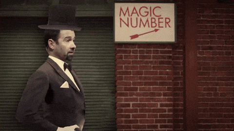 a man in a tuxedo is holding a rabbit and a sign with the number four on it