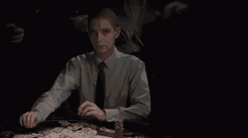 a man in a tie sits at a table with poker chips