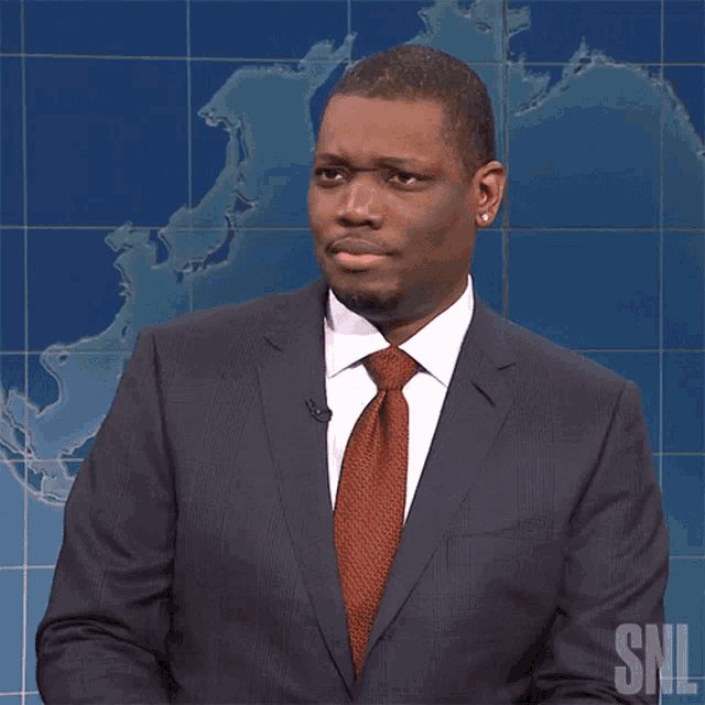 a man in a suit and tie stands in front of a snl map
