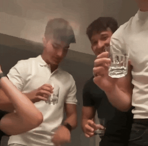 a man in a white shirt is holding a shot glass in his right hand