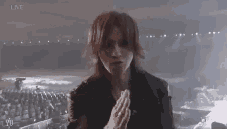 a man with long red hair is praying on a stage .