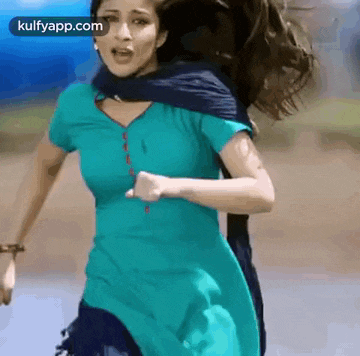 a woman in a blue dress is running across a field .