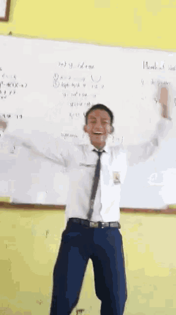 a man in a tie is dancing in front of a whiteboard
