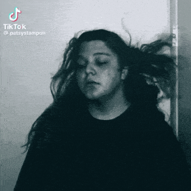 a woman 's hair is blowing in the wind in a black and white photo
