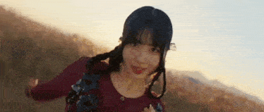 a young woman in a red dress is standing in a field and smiling .