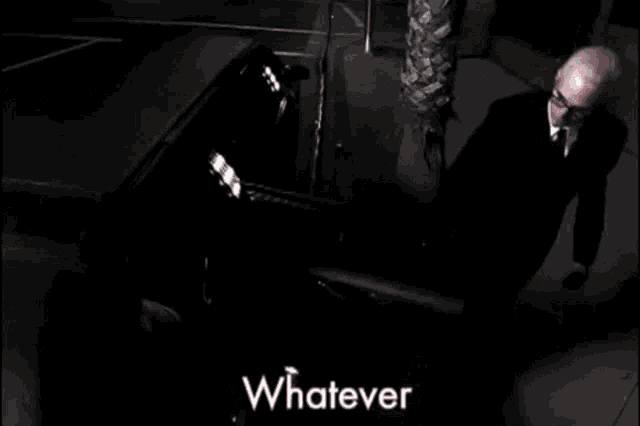 a man in a suit is playing a piano with the words " whatever " written above him