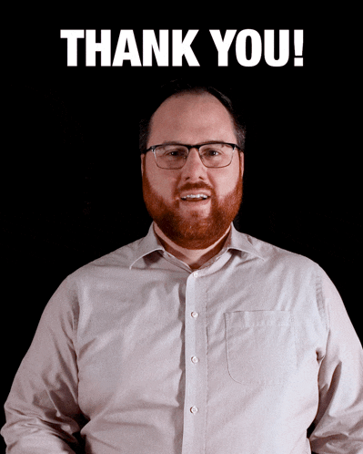 a man with glasses and a beard stands in front of a sign that says thank you