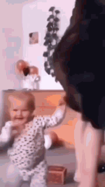 a woman is holding a baby in her arms and the baby is walking .