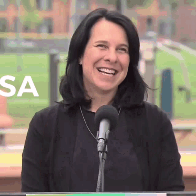 a woman is smiling in front of a microphone and the word sa is behind her