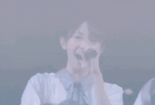 a girl is smoking a cigarette while holding a microphone .