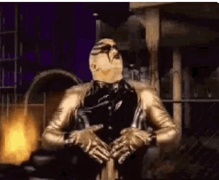 a man in a gold suit is standing in front of a fire in a dark room .
