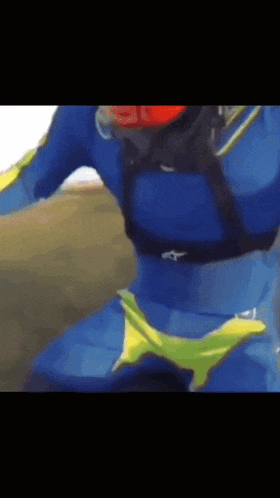 a person wearing a blue alpinestars shirt rides a motorcycle