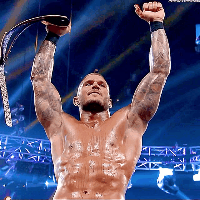a shirtless wrestler is holding a championship belt over his head ..