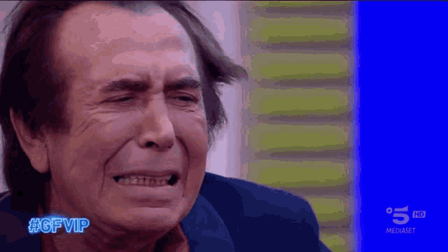a man is crying in front of a blue screen with #gfvip written on it