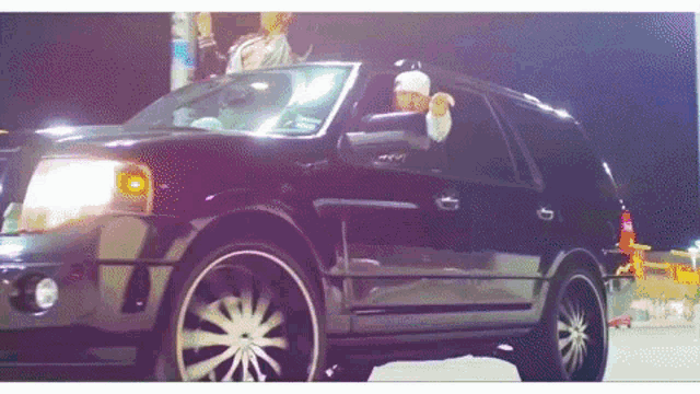 a black suv is parked in a parking lot at night