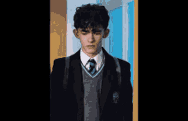 a young man in a school uniform with the letter t on the shoulder