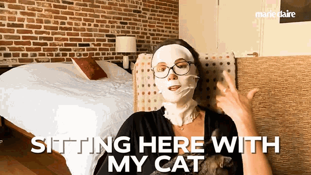 a woman with a mask on her face is sitting in a chair with a cat