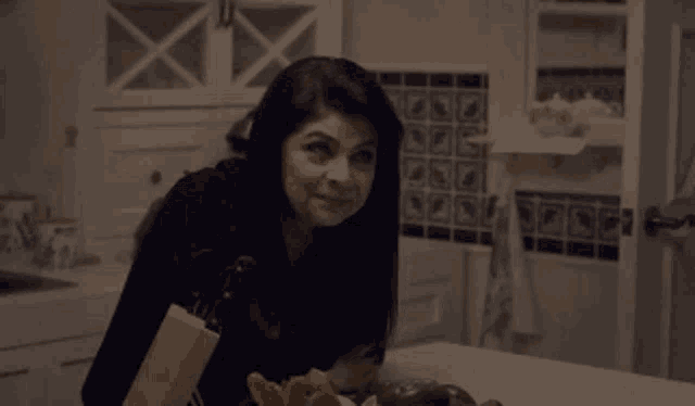 a woman is sitting at a kitchen counter with a knife in her hand