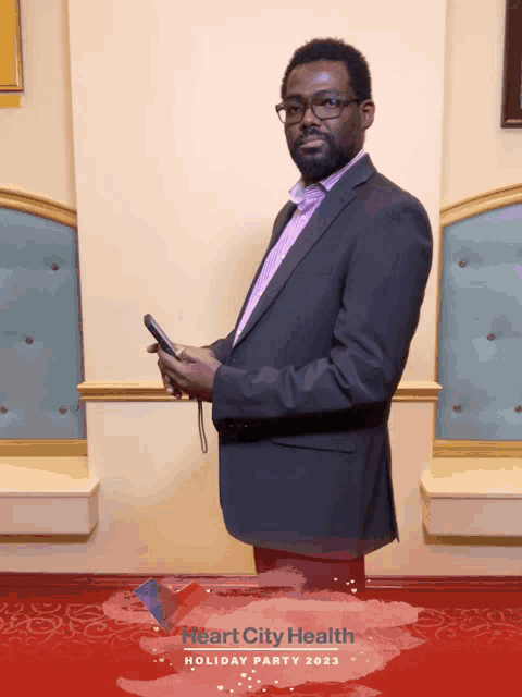 a man in a suit stands in front of a heart city health holiday party