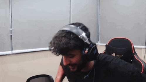 a man with a beard wearing headphones and a gaming chair .