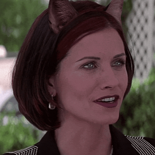 a woman wearing a cat ear headband smiles for the camera
