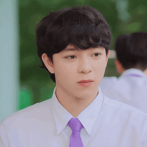 a young man in a white shirt and purple tie