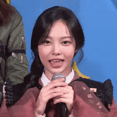 a girl with pigtails is holding a microphone with her tongue out