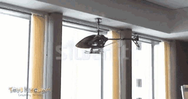 a toy helicopter is hanging from the ceiling in front of a window .