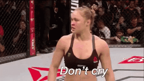 a woman is standing in a boxing ring with the words `` do n't cry '' written on her face .