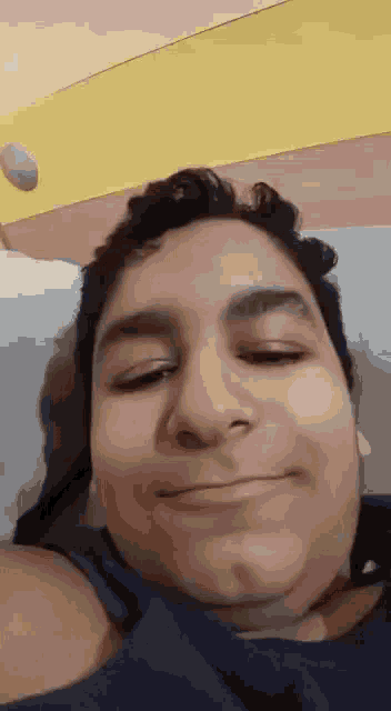 a man is smiling while laying on a bed with a rock in the background .