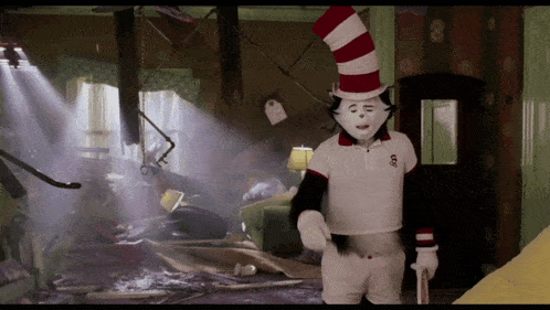 cat in the hat is standing in a messy room with a cane