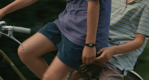 a girl wearing a watch that says ' i love you ' on it is riding a bike with a boy