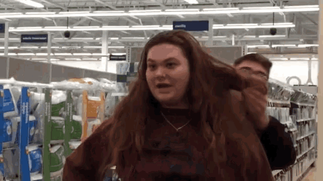a woman is standing in a store with a man holding her hair in front of a sign that says adult tomorrow