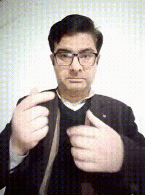 a man wearing glasses and a suit is adjusting his tie ..