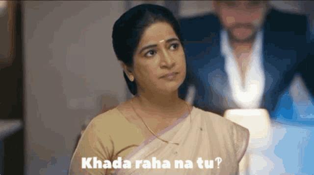 a woman is sitting at a table with a man behind her and the words khada raha na tu written on the bottom