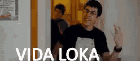 a man in a black shirt is standing in front of a door with the words vida loka on it