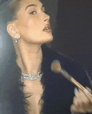 a woman is applying makeup to her face with a brush .