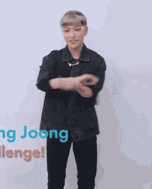 a young man wearing a denim jacket and glasses is dancing .
