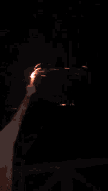 a man is holding a flame in his hand in the dark