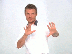 a man in a white shirt and black pants is dancing in front of a white wall