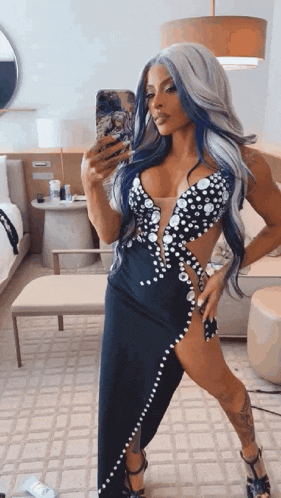 a woman in a black dress is taking a selfie in front of a mirror in a hotel room .