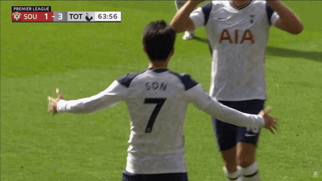 two soccer players hugging each other in front of a scoreboard that says premier league
