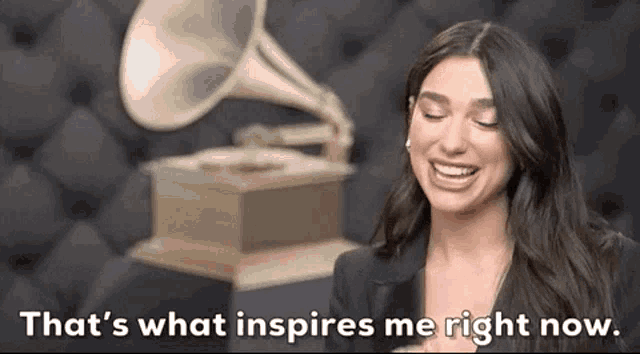 a woman is laughing in front of a grammophone and says `` that 's what inspires me right now . ''
