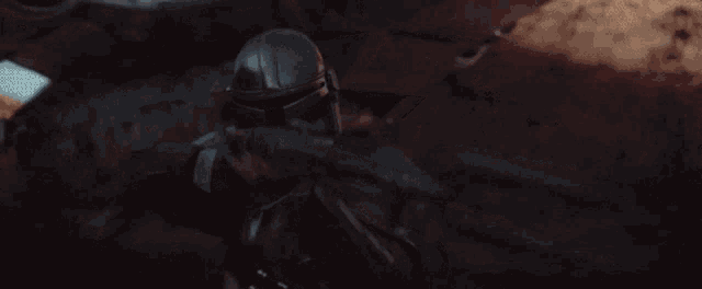 a man in a helmet is holding a gun in front of a building .