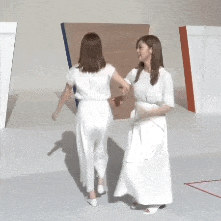 two women in white dresses are standing next to each other holding hands and dancing .